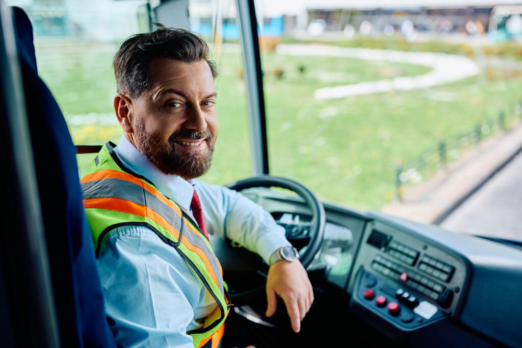 Happy bus driver inside the bus looking at camera.